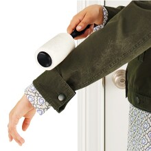 Pessoa usando rolo removedor de fiapos na manga de casaco verde.
